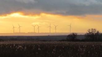 Windturbinen auf einem fernen Hügel im Abendlicht
